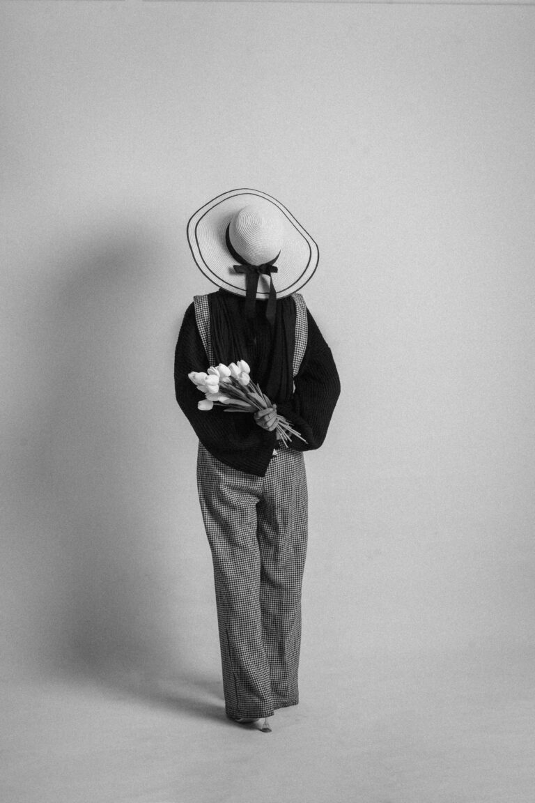 Monochrome portrait of a woman holding tulips, wearing a stylish outfit and hat.